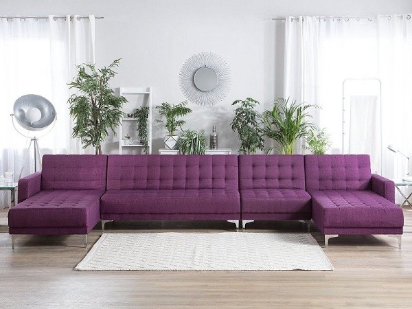 Sofa góc vuông chữ U màu tím thiết kế nút bấm trang trí, chân nâng inox sáng bóng mang vẻ đẹp sang trọng, lãng mạn, nổi bật giữa căn phòng màu trắng tinh khôi